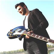 Giovane insegnante di chitarra elettrica moderna impartisce lezioni di musica a grandi e piccoli